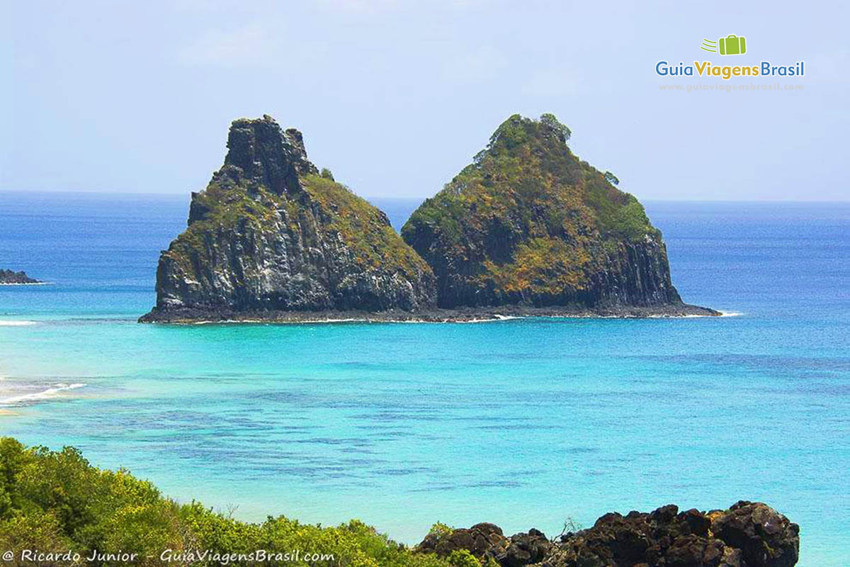 Imagem do Morro Dois Irmãos envolto das águas cristalinas da Praia do Boldro, em Fernando de Noronha, Pernambuco, Brasil.